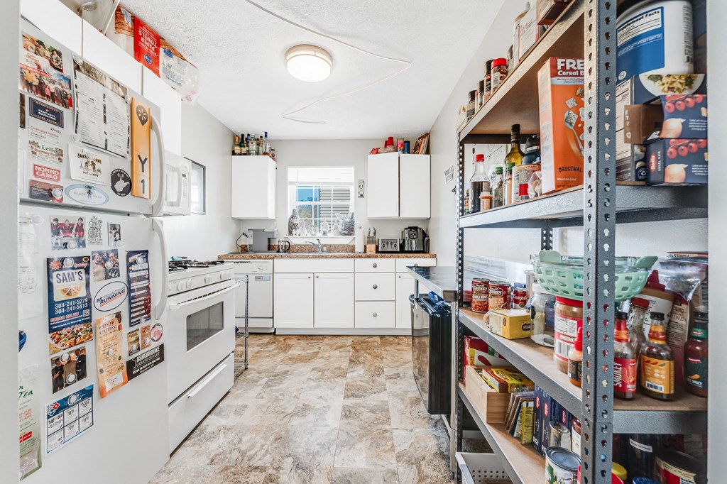 A kitchen with a white fridge covered in flyers and a white stove.