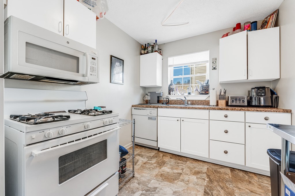 A kitchen with a white stove and white cabinets.