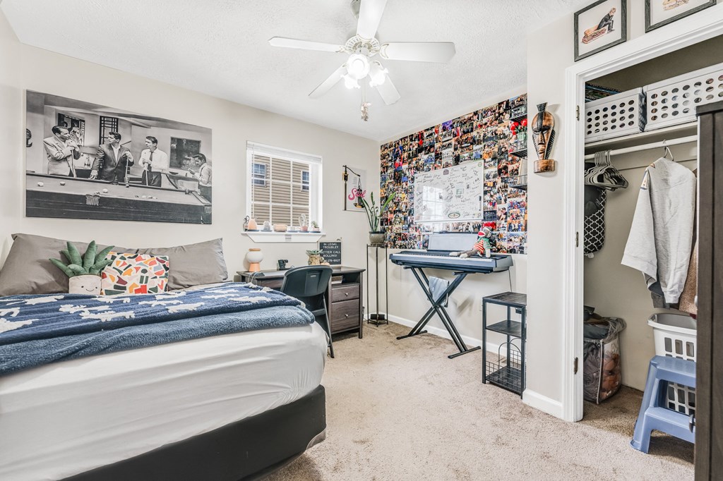 A bedroom with a bed, desk, and a wall covered in pictures and memorabilia.