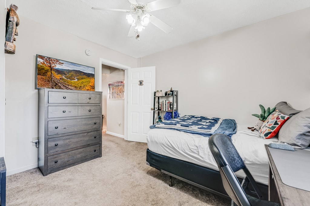 A bedroom with a bed, dresser, and chair.
