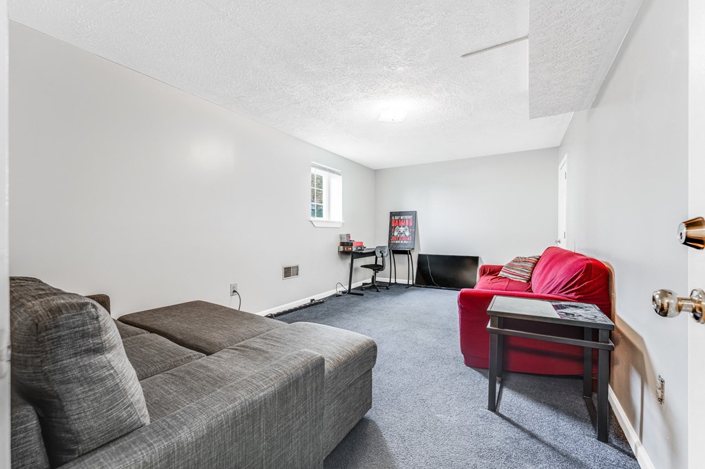 A living room with a grey couch and a red chair.