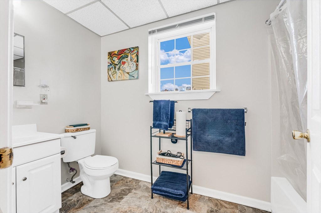 A bathroom with a toilet, a towel rack with two towels, and a picture on the wall.