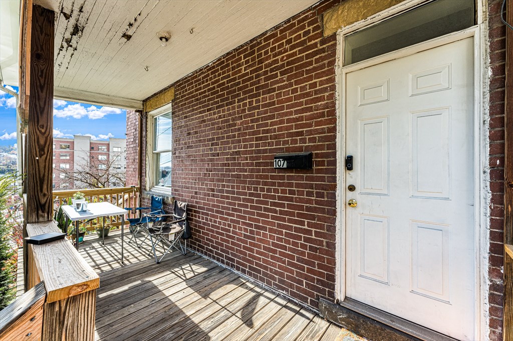 A small balcony with a table and chairs is attached to a brick building.