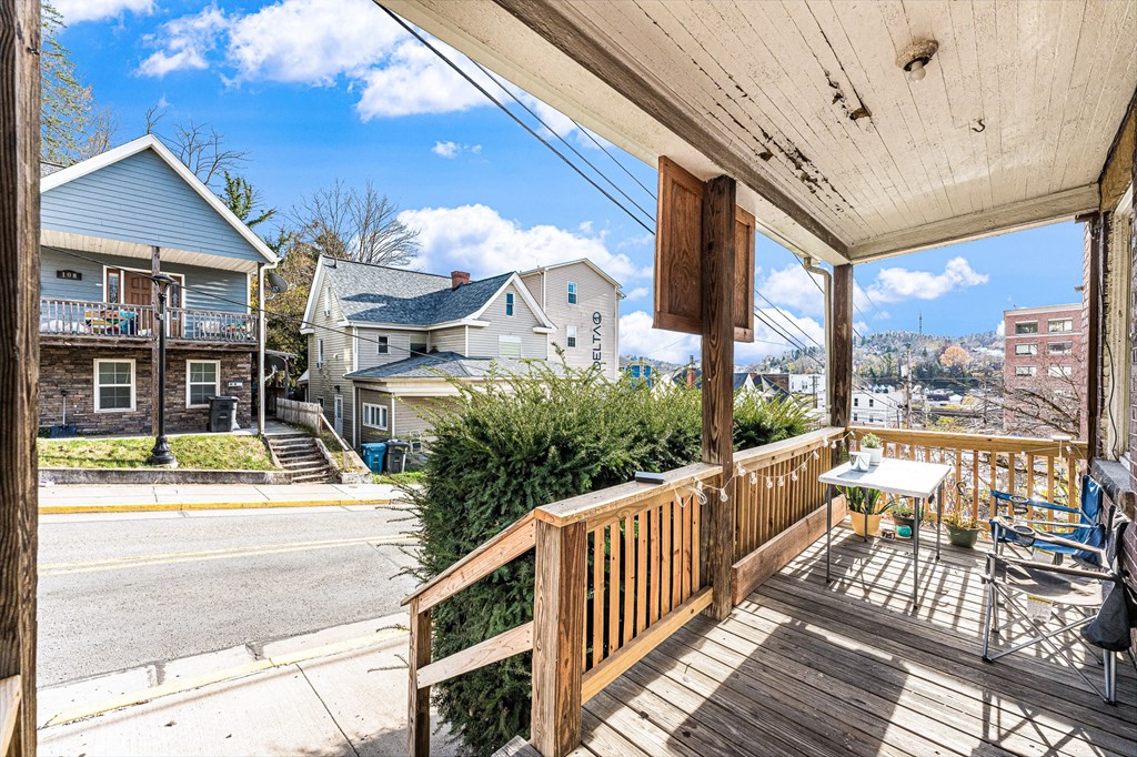 A wooden deck with a table and chairs overlooks a street.
