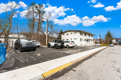 A parking lot with cars and a white building in the background.