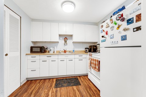 A kitchen with white cabinets and a refrigerator covered in magnets.