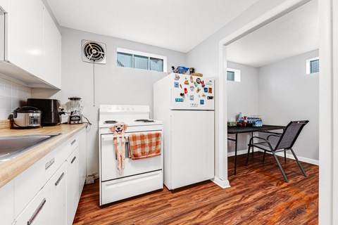 A small kitchen with a white fridge and wooden floors.