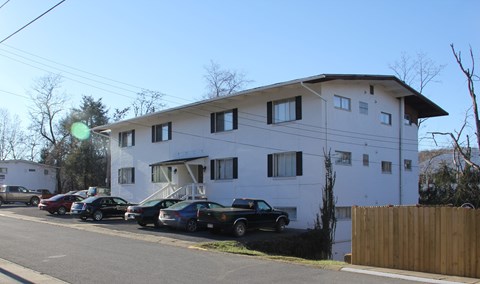 A white two-story building with a black car parked in front.