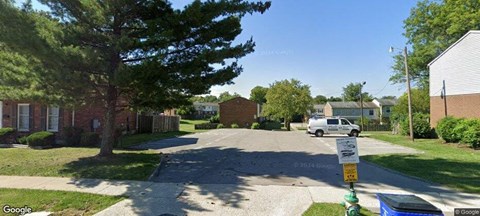 A street view of a residential area with houses on both sides and a car parked on the street.