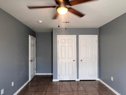 A room with a ceiling fan and two doors.