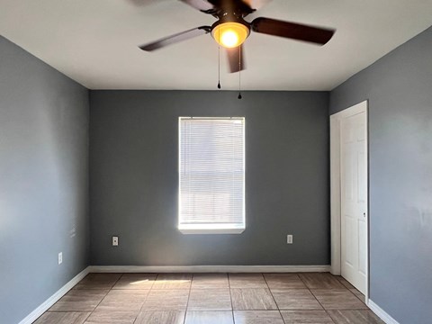 A room with a ceiling fan and a window with blinds.