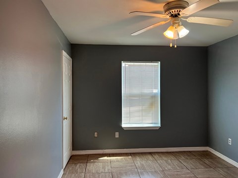 A room with a ceiling fan and a window with blinds.