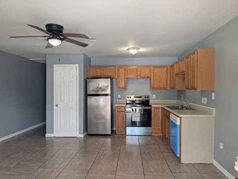 A kitchen with a refrigerator, oven, and cabinets.