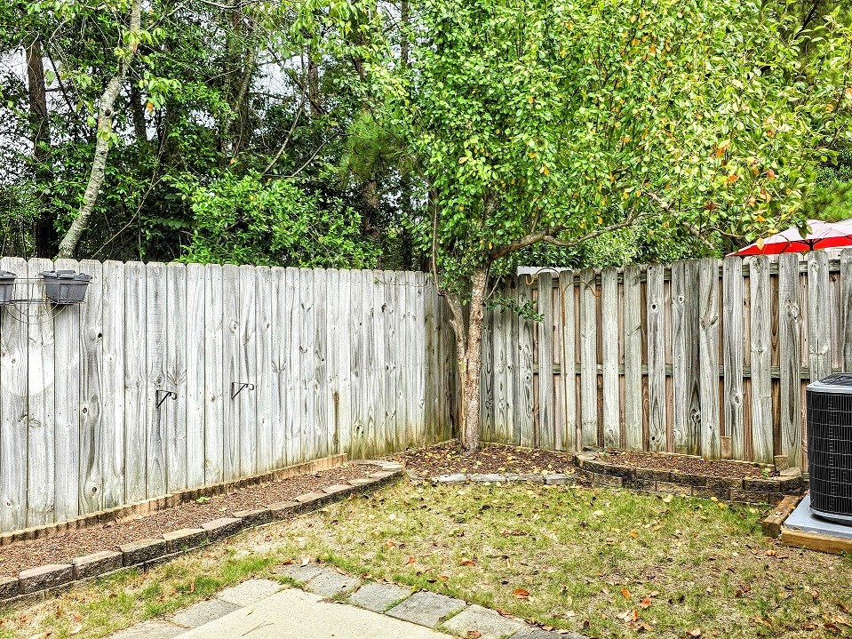 a backyard with a wooden fence and a tree