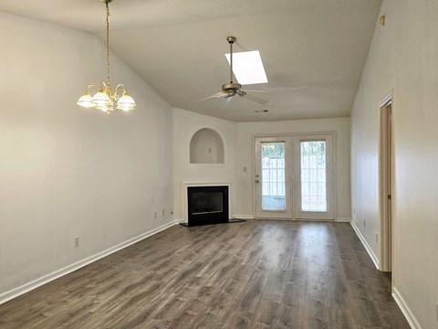 an empty living room with a fireplace and a ceiling fan