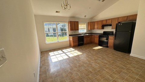an empty kitchen with black appliances and a window