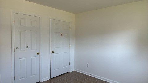 a bedroom with two closets and a tiled floor and two doors