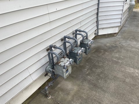 three generators outside of the side of a house