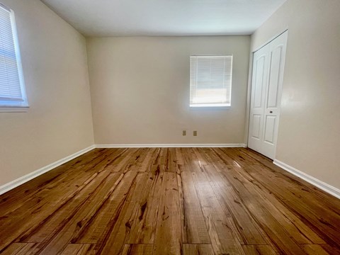 an empty bedroom with wooden floors and white walls