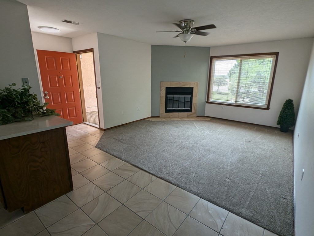 an empty living room with a fireplace and a ceiling fan