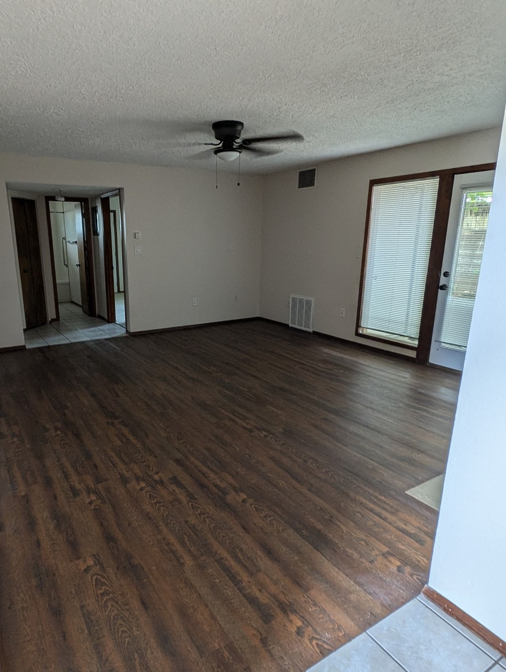 an empty living room with wooden floors and a ceiling fan