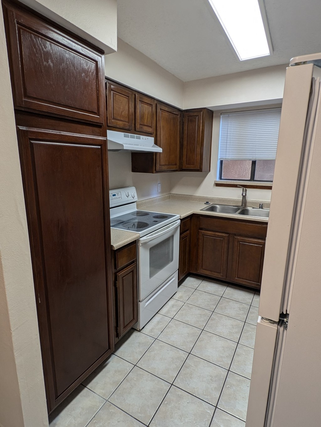 an empty kitchen with wooden cabinets and white appliances