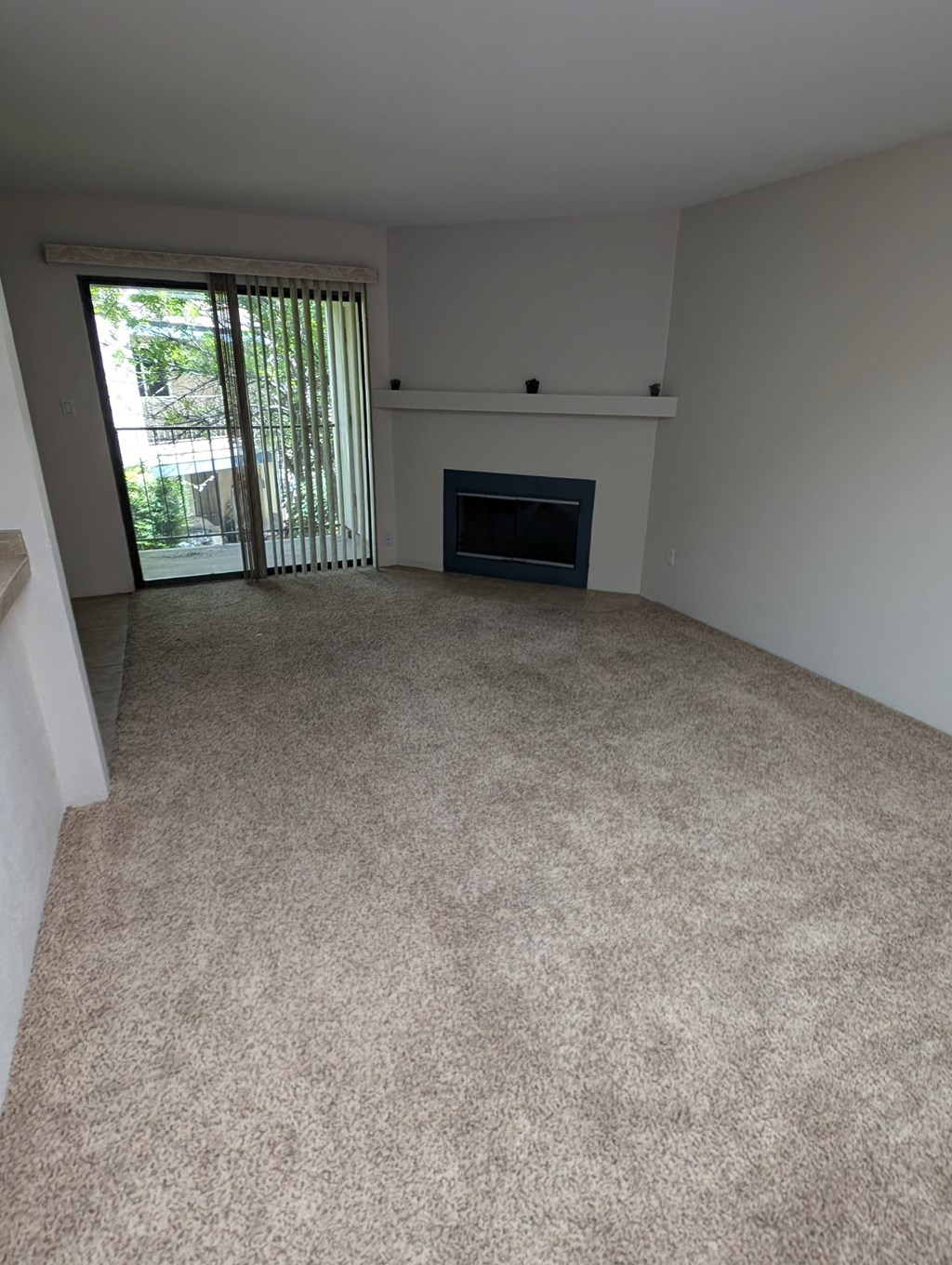 an empty living room with a fireplace and a sliding glass door