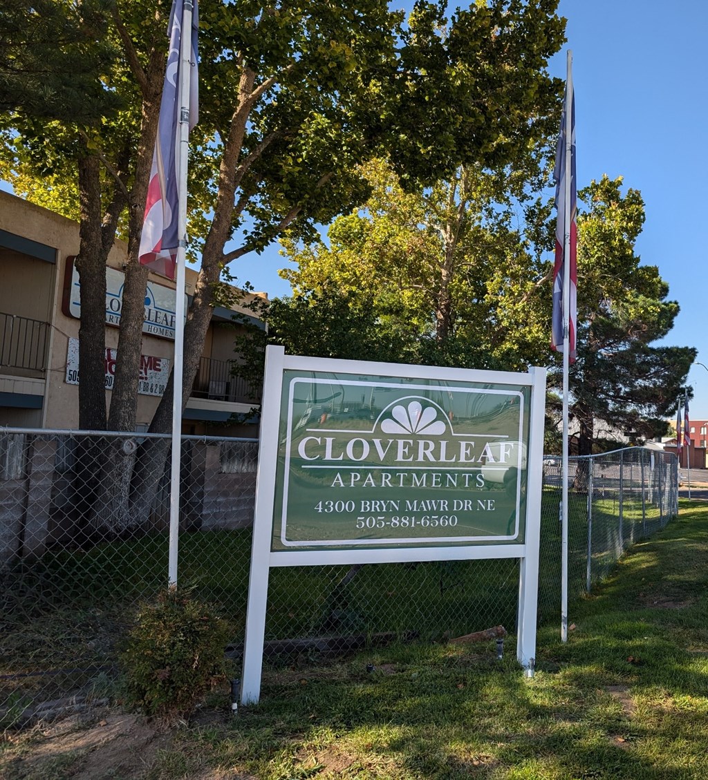 a sign for cloverleaf apartments in front of some flags