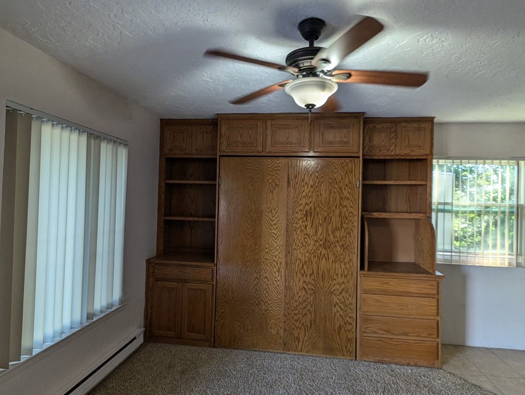 an empty bedroom with a ceiling fan and a closet