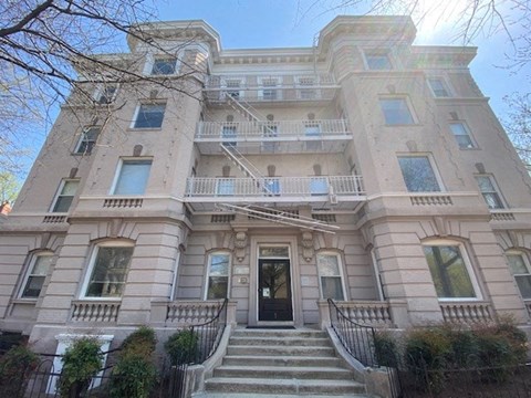 A large, two-story building with a black door and stairs leading up to it.