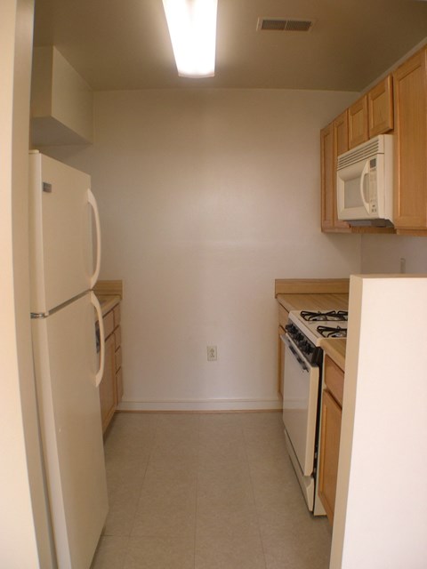 A kitchen with a refrigerator, stove, and microwave.