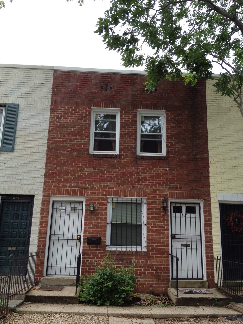 A red brick house with a black gate in front.