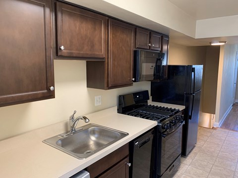 A kitchen with black appliances and wooden cabinets.