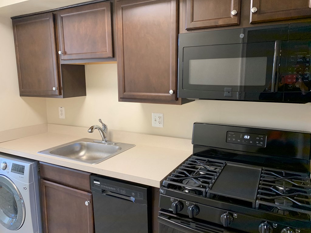 A black stove top oven sits under a microwave in a kitchen.