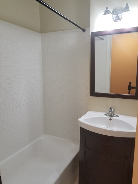 a small bathroom with a sink and a tub and a mirror