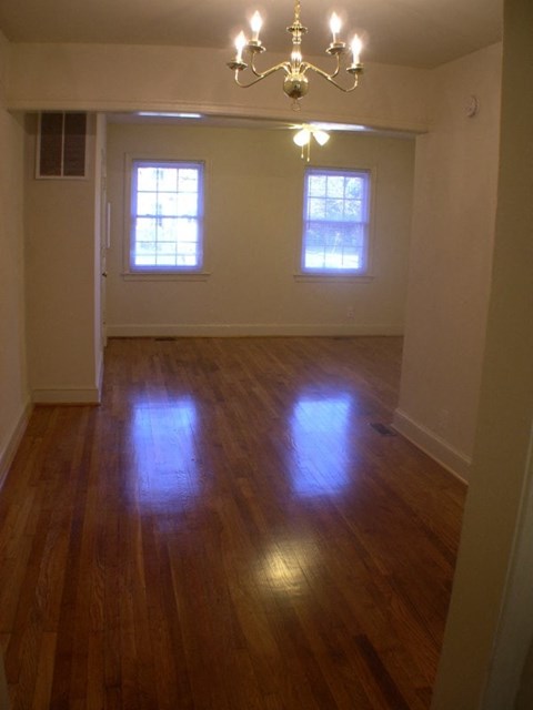 A room with a chandelier and two windows.