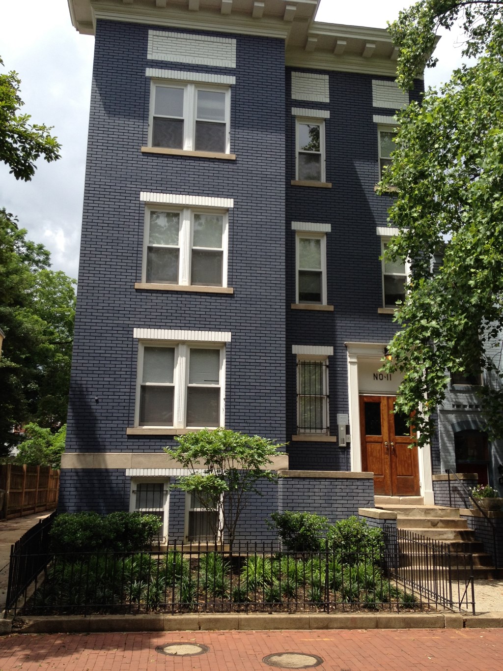 A blue brick building with a black iron fence in front.