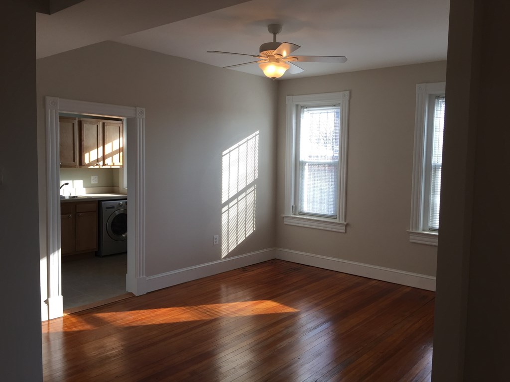 A room with a ceiling fan and two windows.