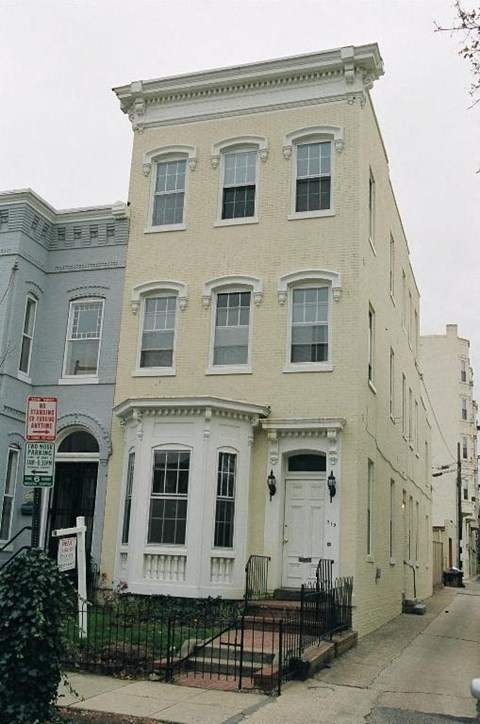 A white building with a black fence in front.