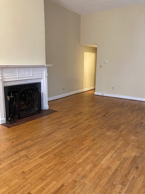 A room with a fireplace and wood flooring.