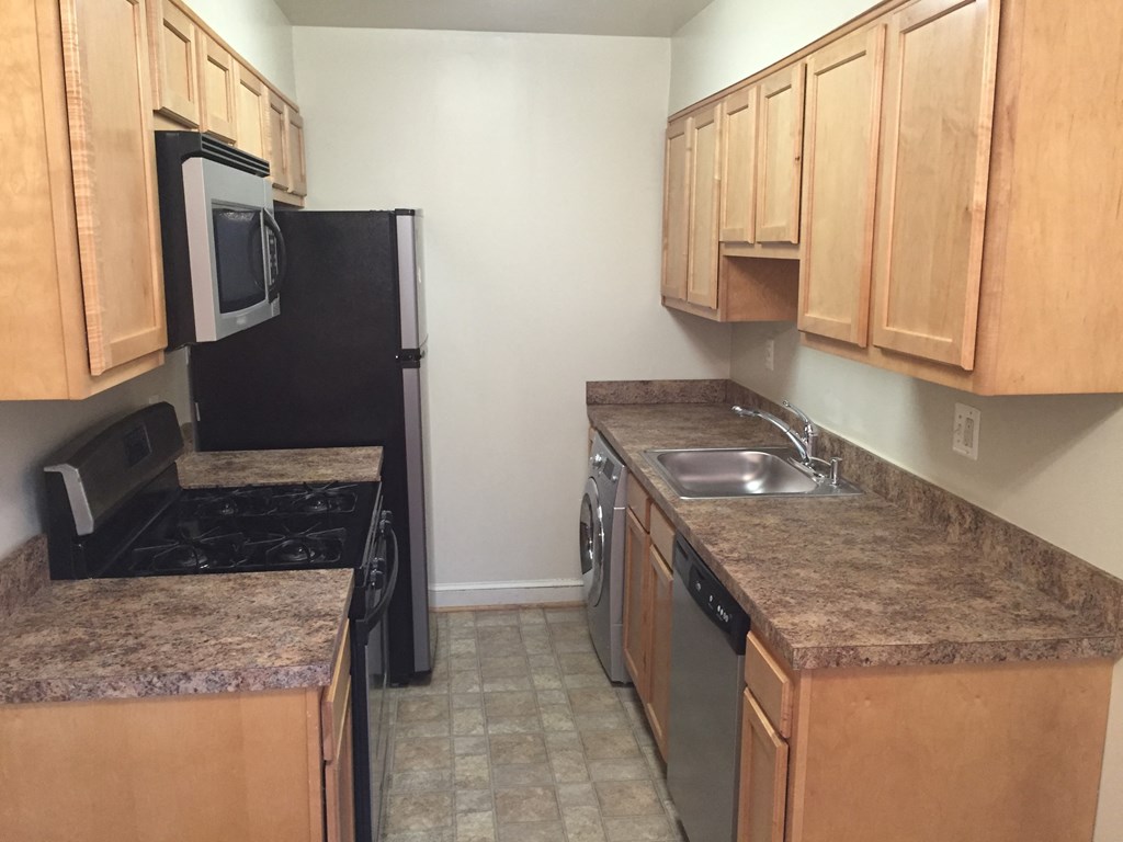 a kitchen with black appliances and granite counter tops and wooden cabinets