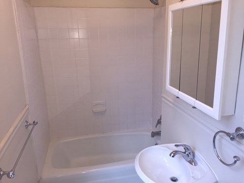 A white bathroom with a tub, sink and mirror.