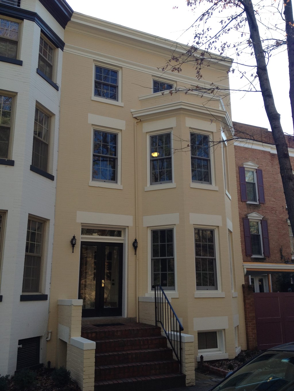 A white and yellow building with a black door and steps leading up to it.
