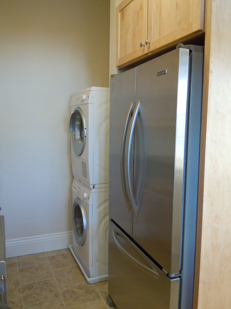 A stainless steel refrigerator and washing machine in a kitchen.