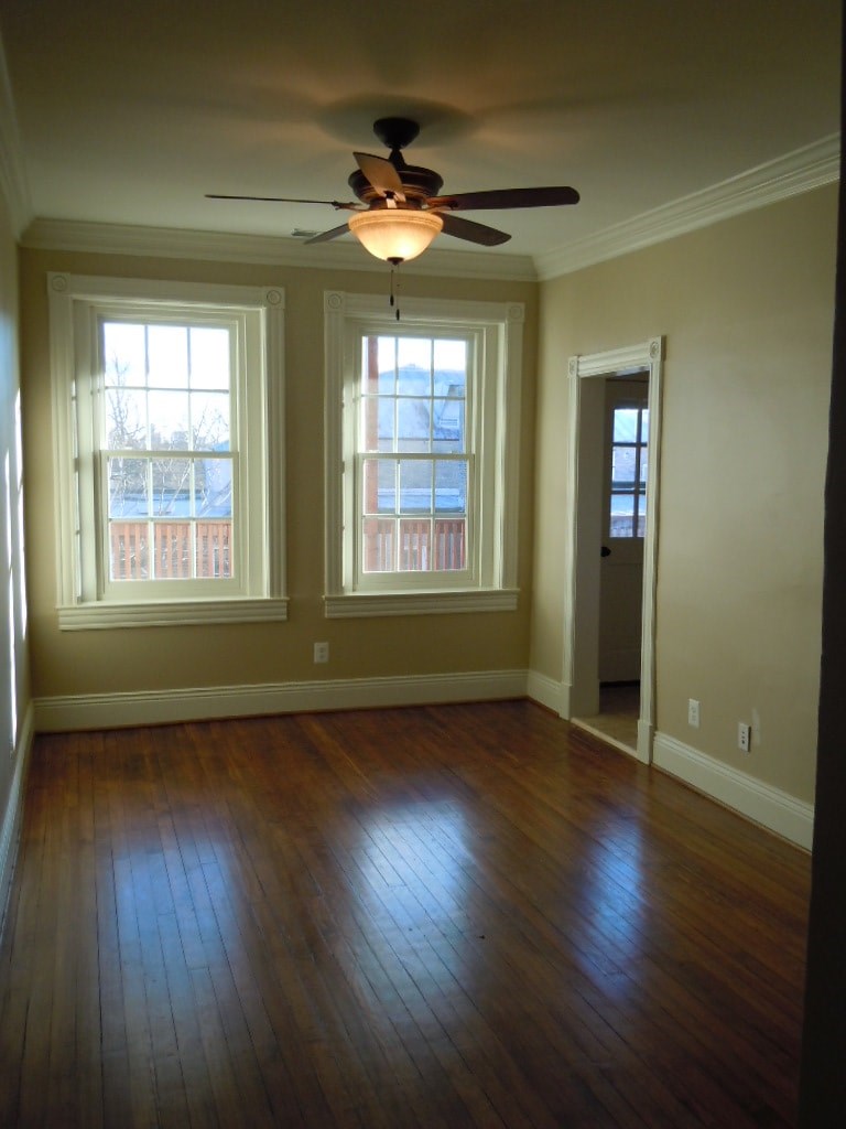 A room with a ceiling fan and two windows.