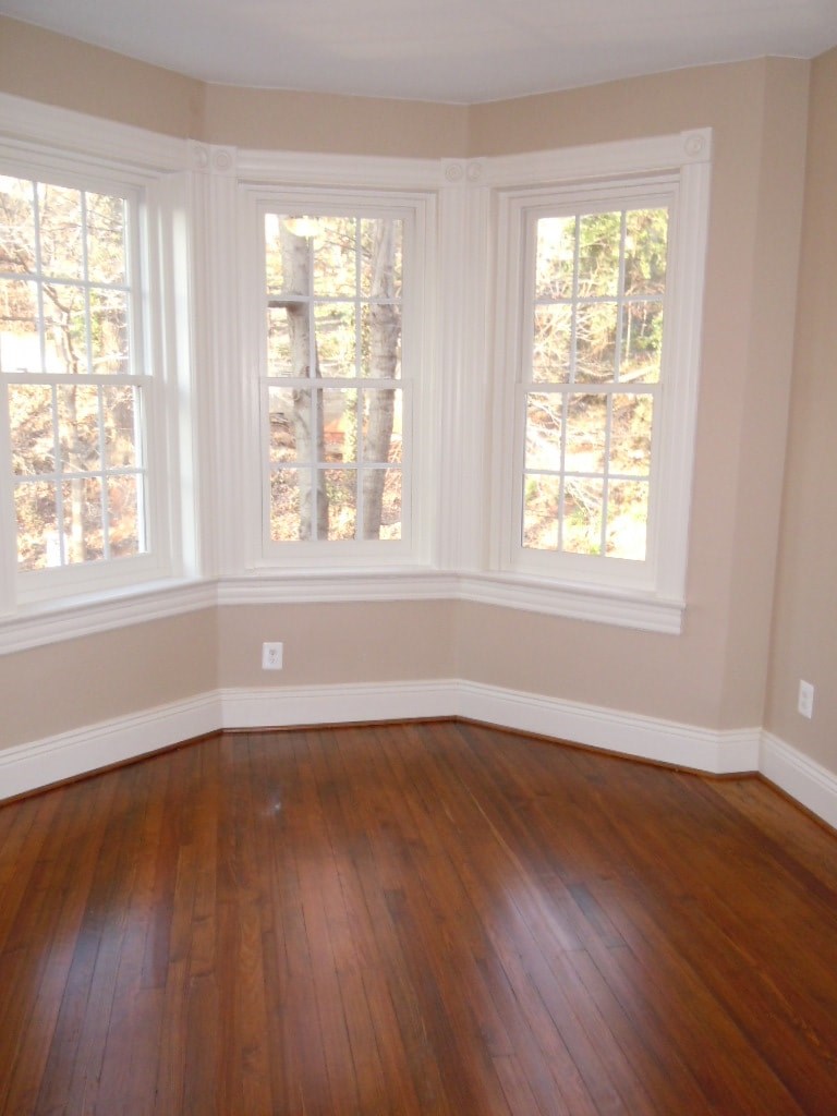 A room with wood floors and three windows.