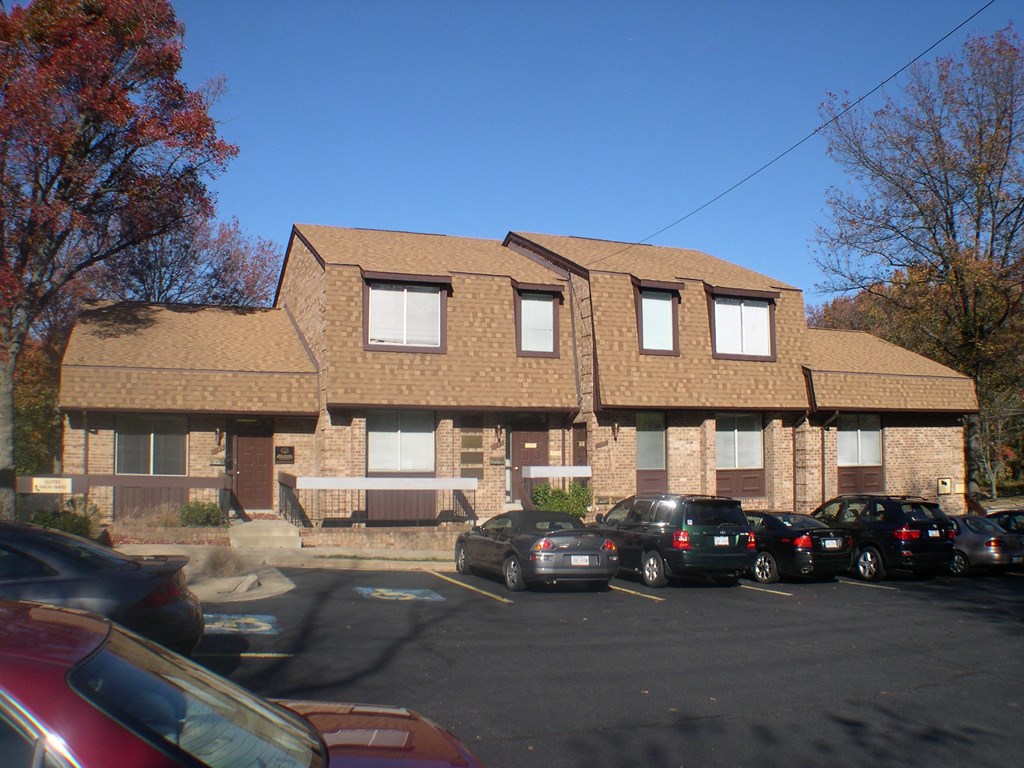 a parking lot with cars in front of a brick apartment building