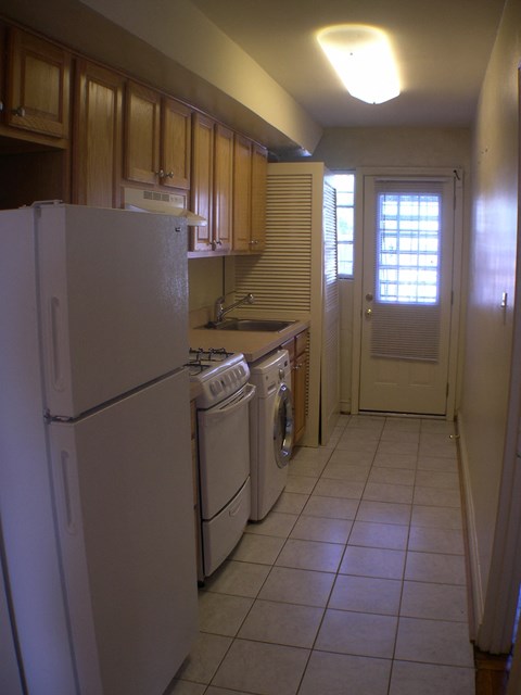 A kitchen with a white refrigerator and a washer and dryer unit.