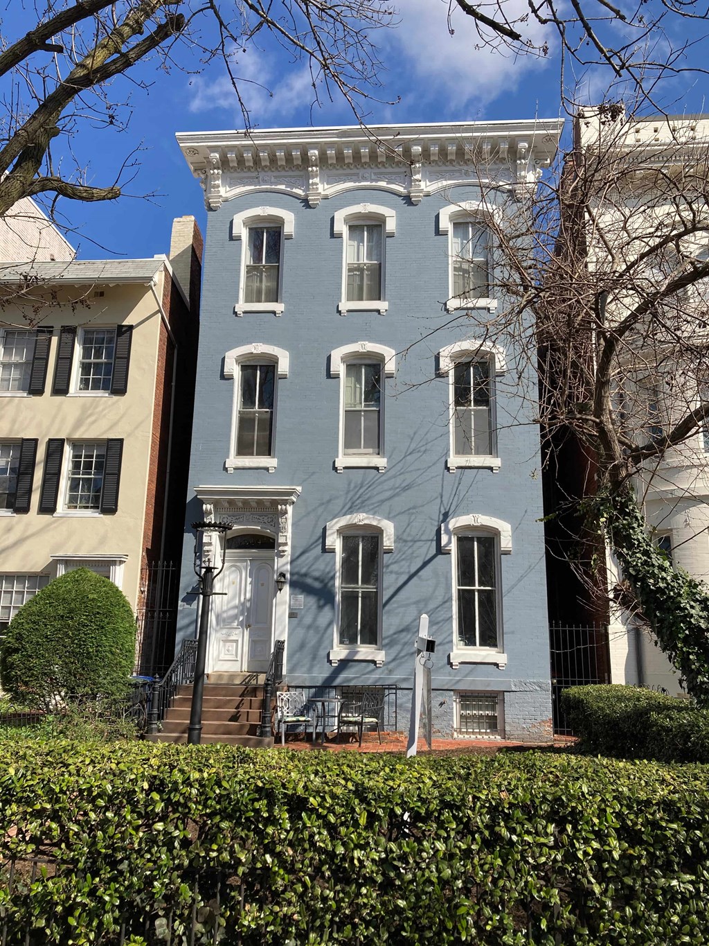A blue building with white trim and windows sits between two other buildings.