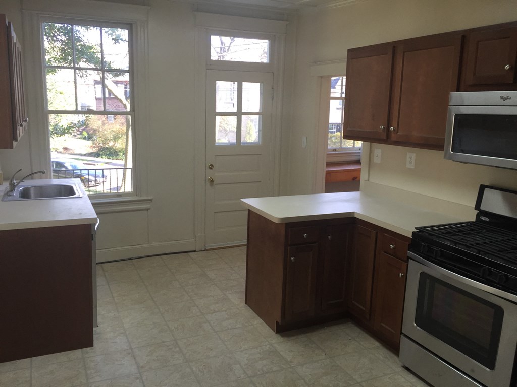 A kitchen with white appliances and brown cabinets.